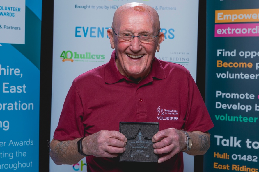 Outstanding Volunteer Award winner Graham stands holding his award with a big smile.