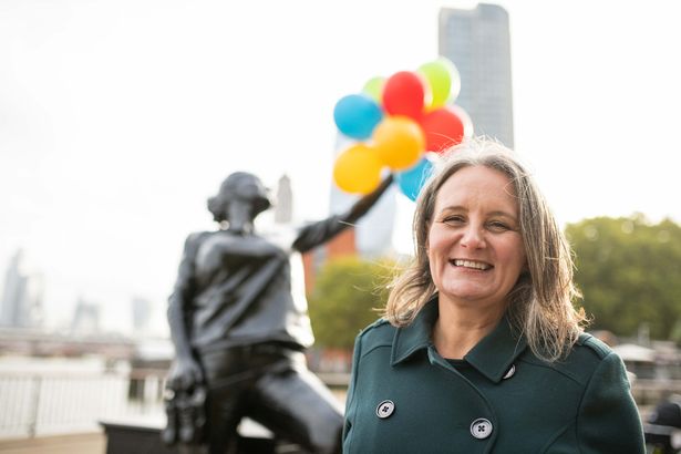 Volunteer Jo smiles in front of the statue of her in London for UK's kindest hero