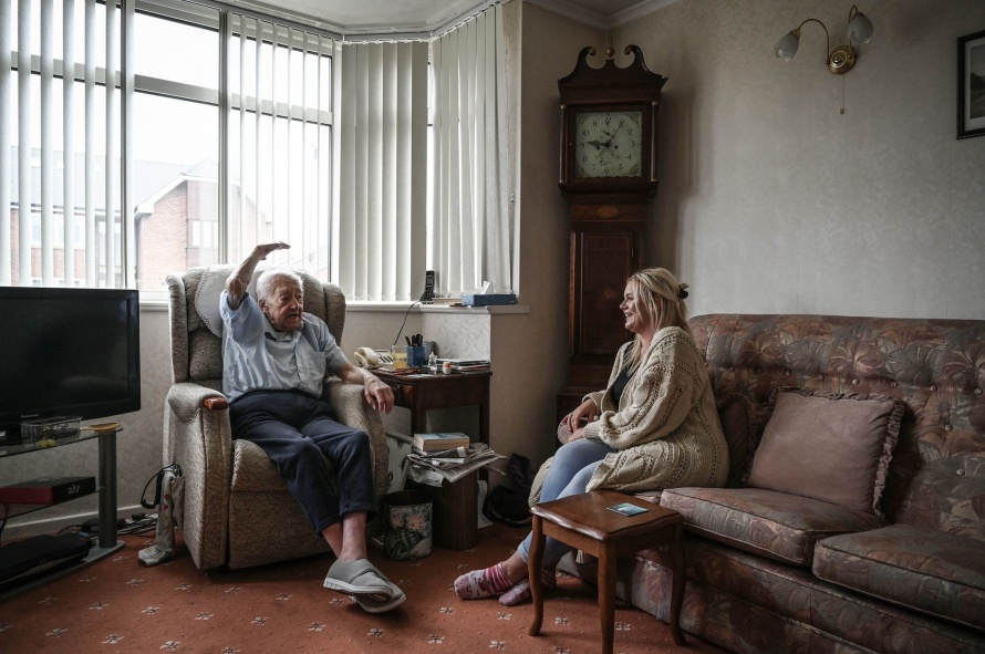 Volunteer Befriender Lucy sitting talking to Alan on his sofa at home 